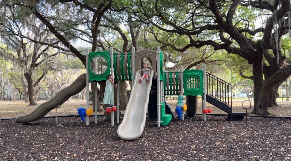 Children playing on outdoor playground slide in park setting