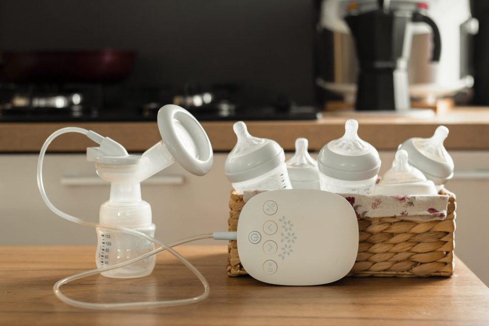 How often should i pump and breastfeed? A quick guide for new moms Electric breast pump and bottles for breasting milk in a wicker basket on a wooden table