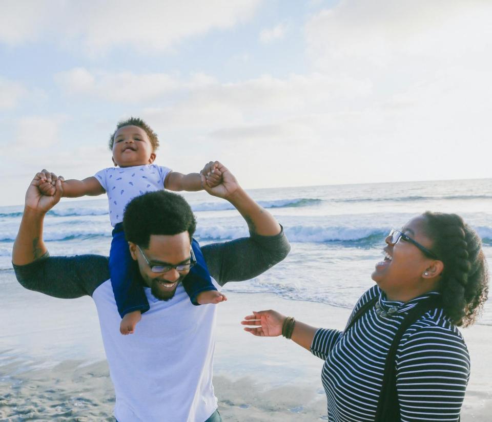 Resilience, not perfection: 3 tips to parent through pressure without losing yourself Black family smiling at the beach symbolizing resilience and joyful parenting moments for an article about resilience, not perfection: 3 tips to parent through pressure without losing yourself