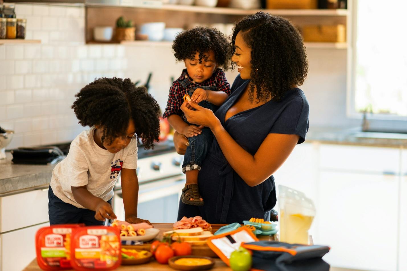 Resilience, not perfection: 3 tips to parent through pressure without losing yourself Black mother cooking with kids showing imperfect parenting filled with love and presence for an article about resilience, not perfection: 3 tips to parent through pressure without losing yourself
