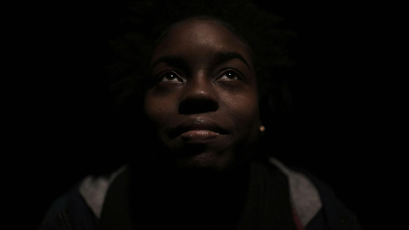 Black teen looking upward in low light, symbolizing hope amid mental health challenges and housing instability in phoenix for an article about invisible in plain sight: black teens in mental health crisis throughout phoenix