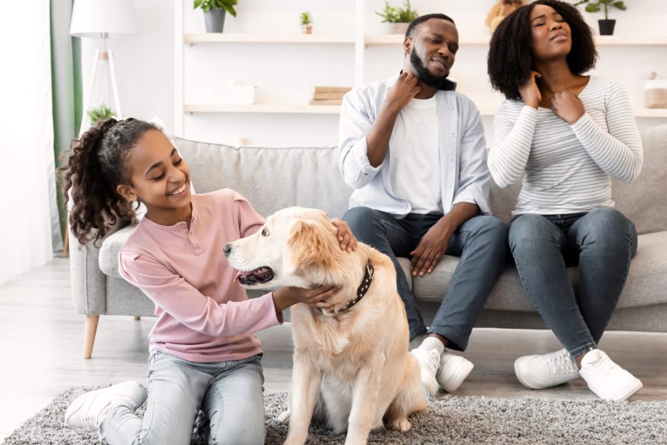Pest control myths for parents debunked: what you need to know for safe home protection Black family scratching while dog sits nearby indoors, highlighting pest control myths and allergic reactions from indoor pests for an article titled, "pest control myths for parents debunked: what you need to know for safe home protection. "