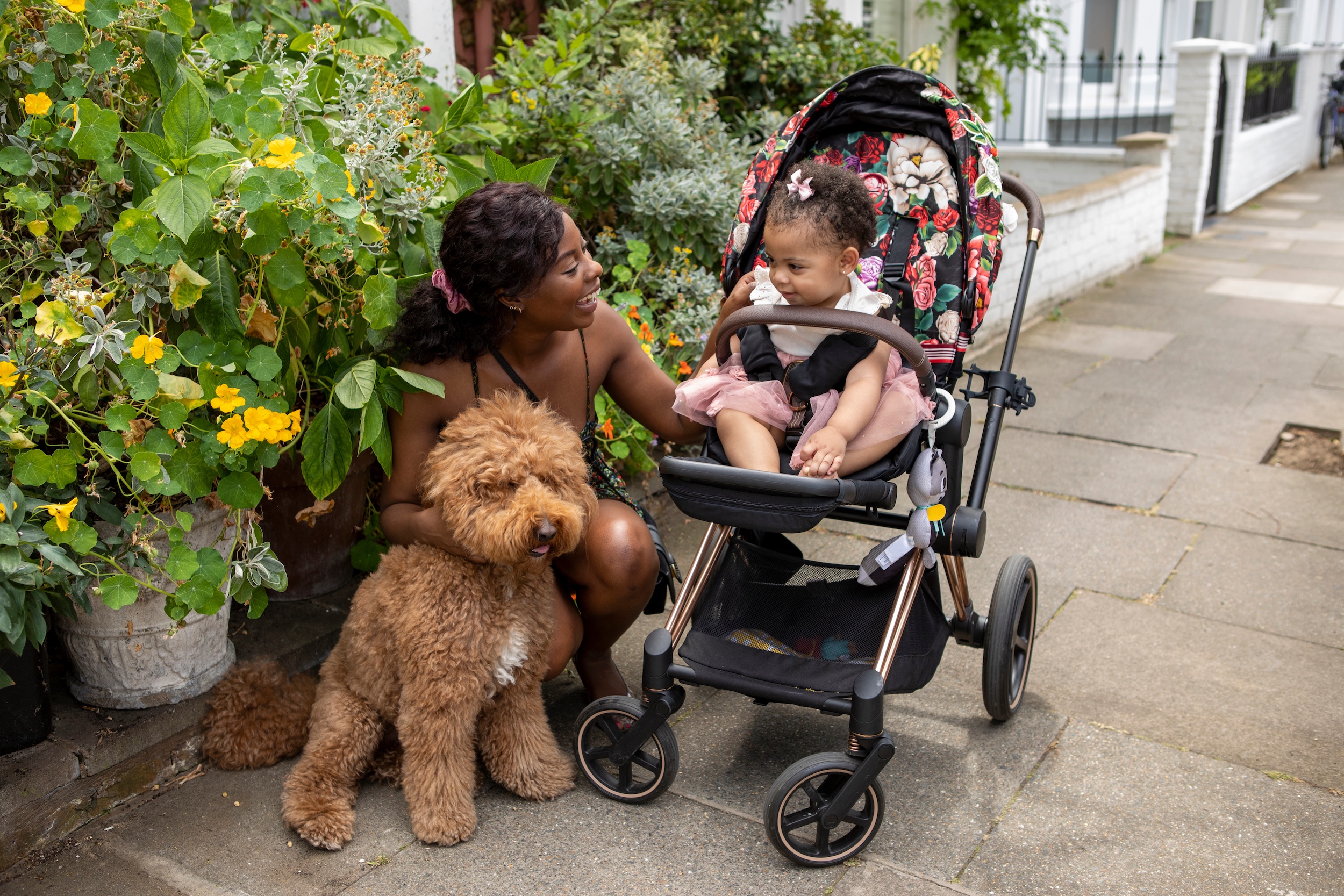 Why every busy parent needs a fold-up pushchair: convenience for family life A busy parent smiling at her baby in a fold-up pushchair with a dog by her side, highlighting convenience for family life and the benefits of a compact stroller