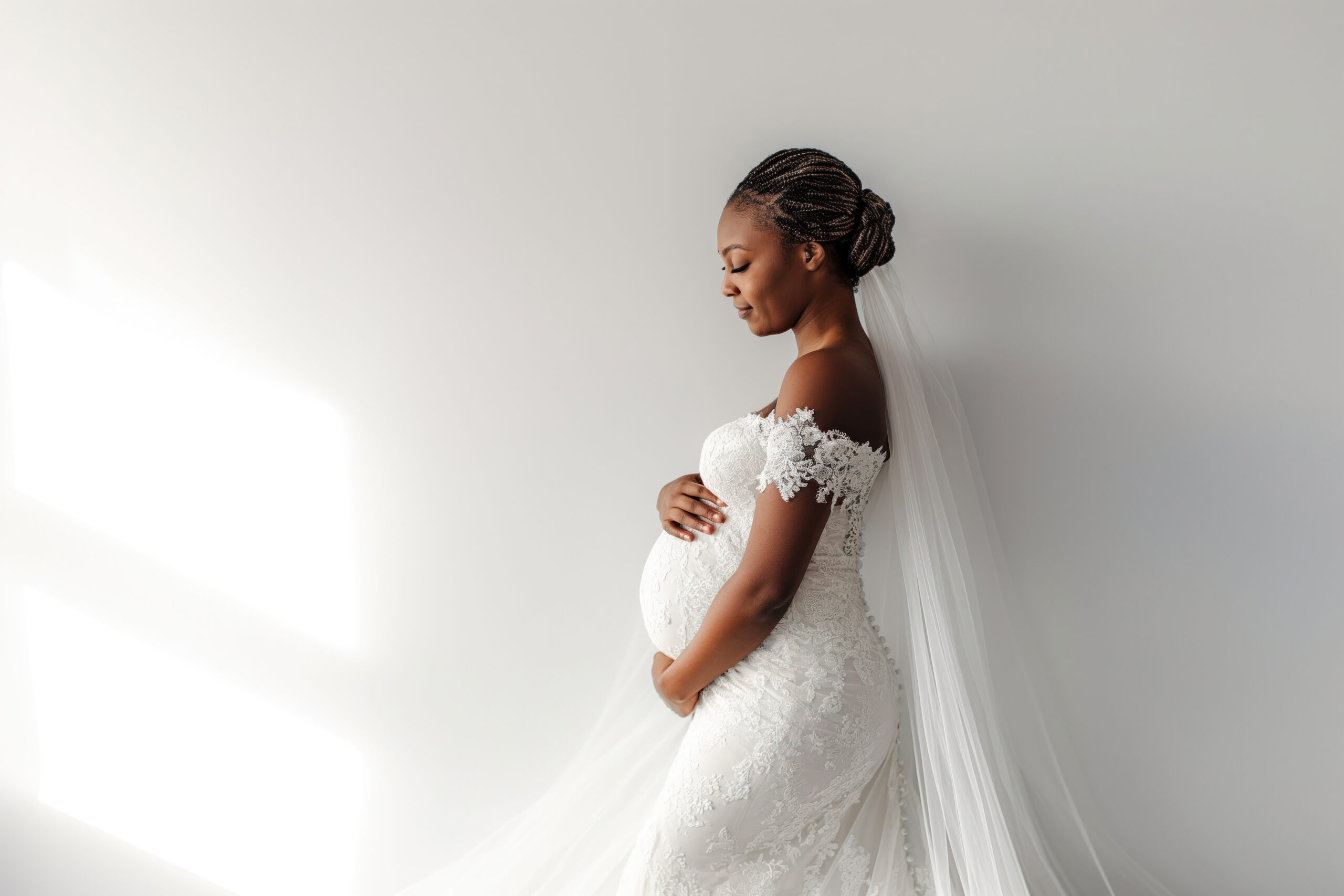 How to plan your wedding when pregnant: glowing down the aisle with love A glowing pregnant black bride in a lace wedding dress stands in profile, showing how to plan your wedding when pregnant with beauty and confidence.