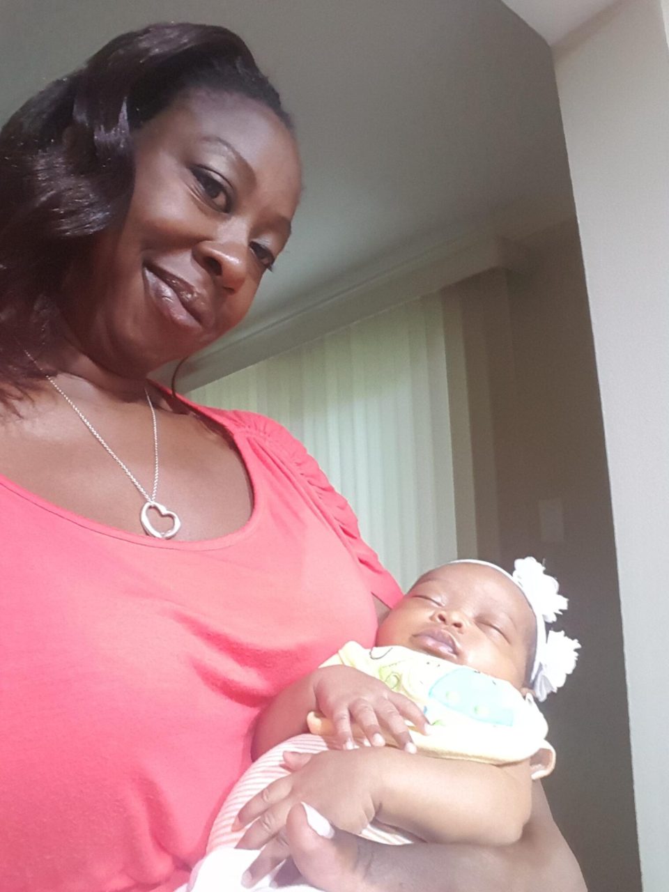 Jana holding her baby in a coral shirt, both smiling, radiating warmth and motherhood for an article about black, single, and proud: why more black women are choosing motherhood on their own terms.