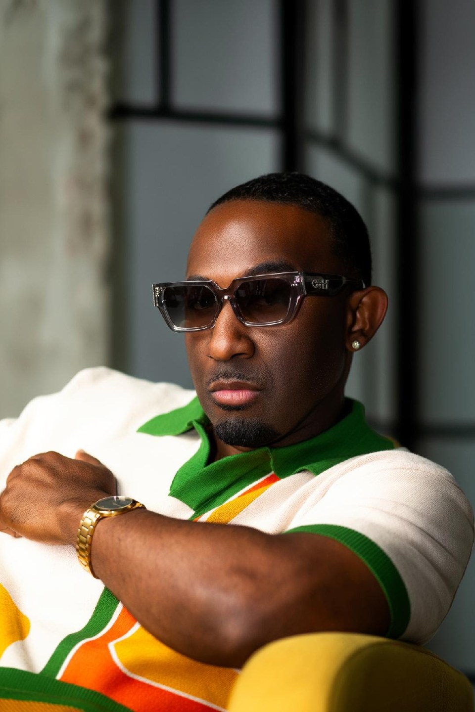 R&b singer denaron on music, fatherhood, and raising a young queen Portrait of r&b artist denaron wearing stylish sunglasses and a retro-inspired polo shirt, posing with confidence.