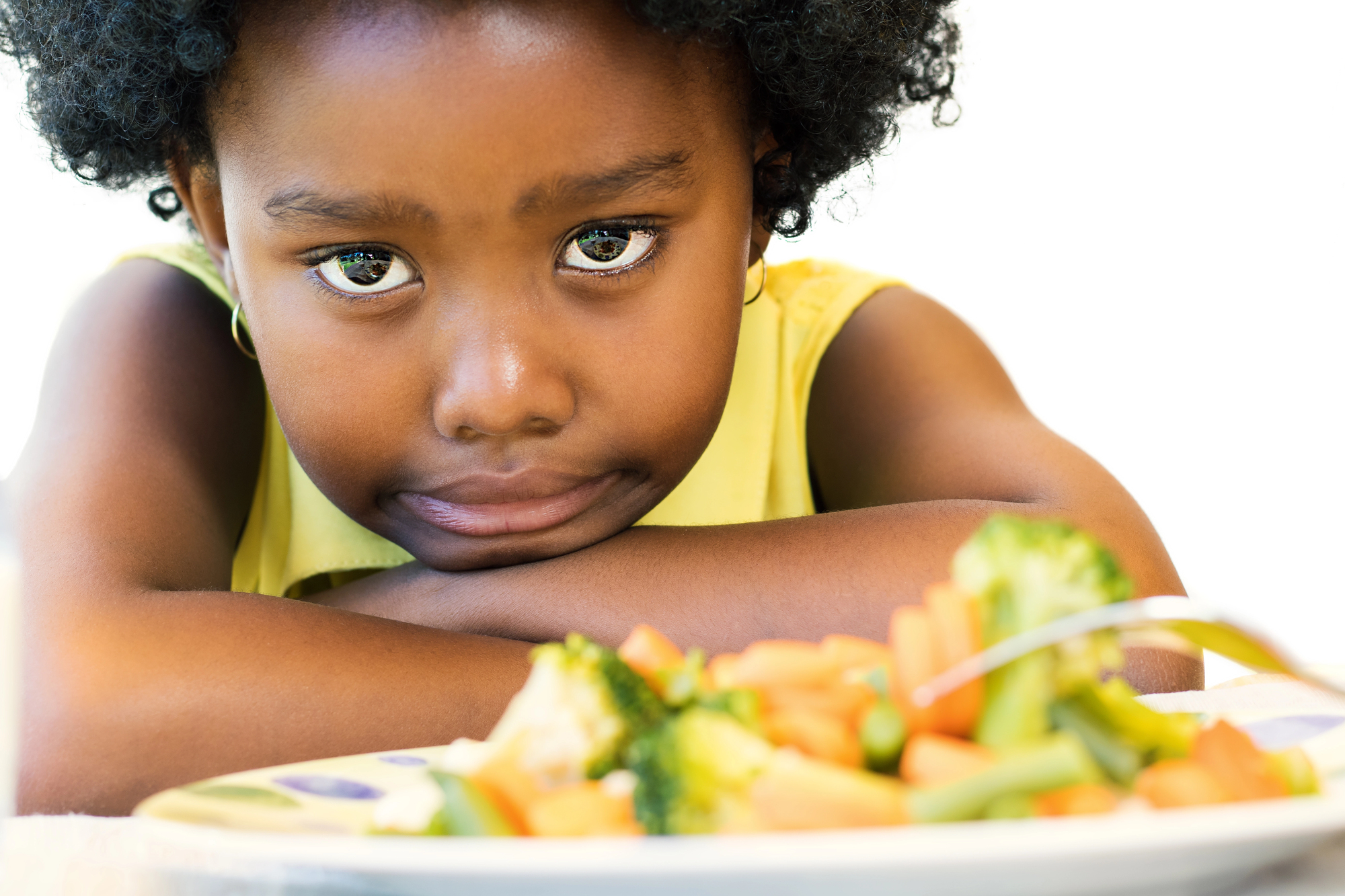 An african american girl not wanting to eat her vegetables because she is picky eaters.