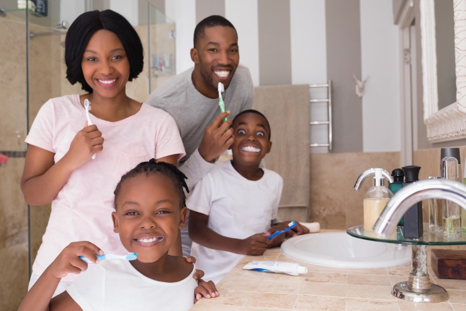 Why every family needs a trusted family dentist An african american family brushes their teeth together for an article on why every family needs a trusted family dentist