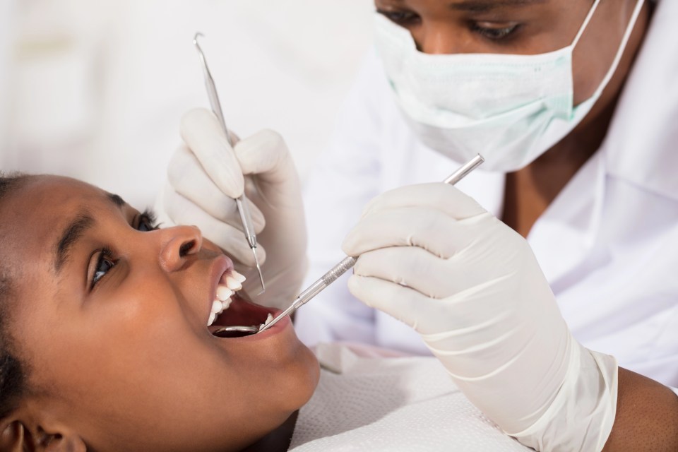Why every family needs a trusted family dentist An african american dentist works on the mouth of an african american girl for an article on why every family needs a trusted family dentist