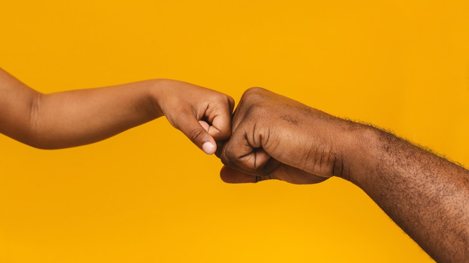 An african american child and father bump fists for an article titled, "5 ways to discuss mental health with your children"