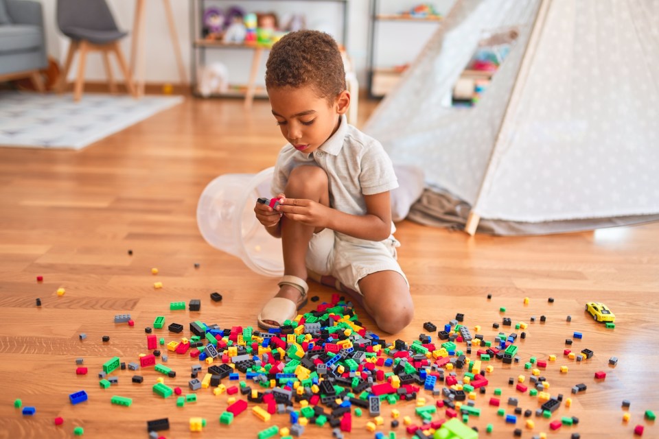 Identifying unsafe toys: a guide to keeping your kids safe Beautiful african american toddler playing with small building blocks that could be unsafe toys