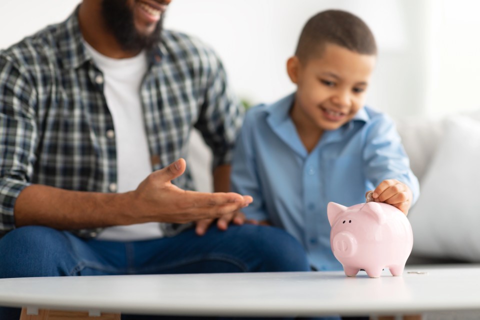 A single dad helps his son put money in their piggy bank for an article about 4 financial tips for single parents to secure their family’s future