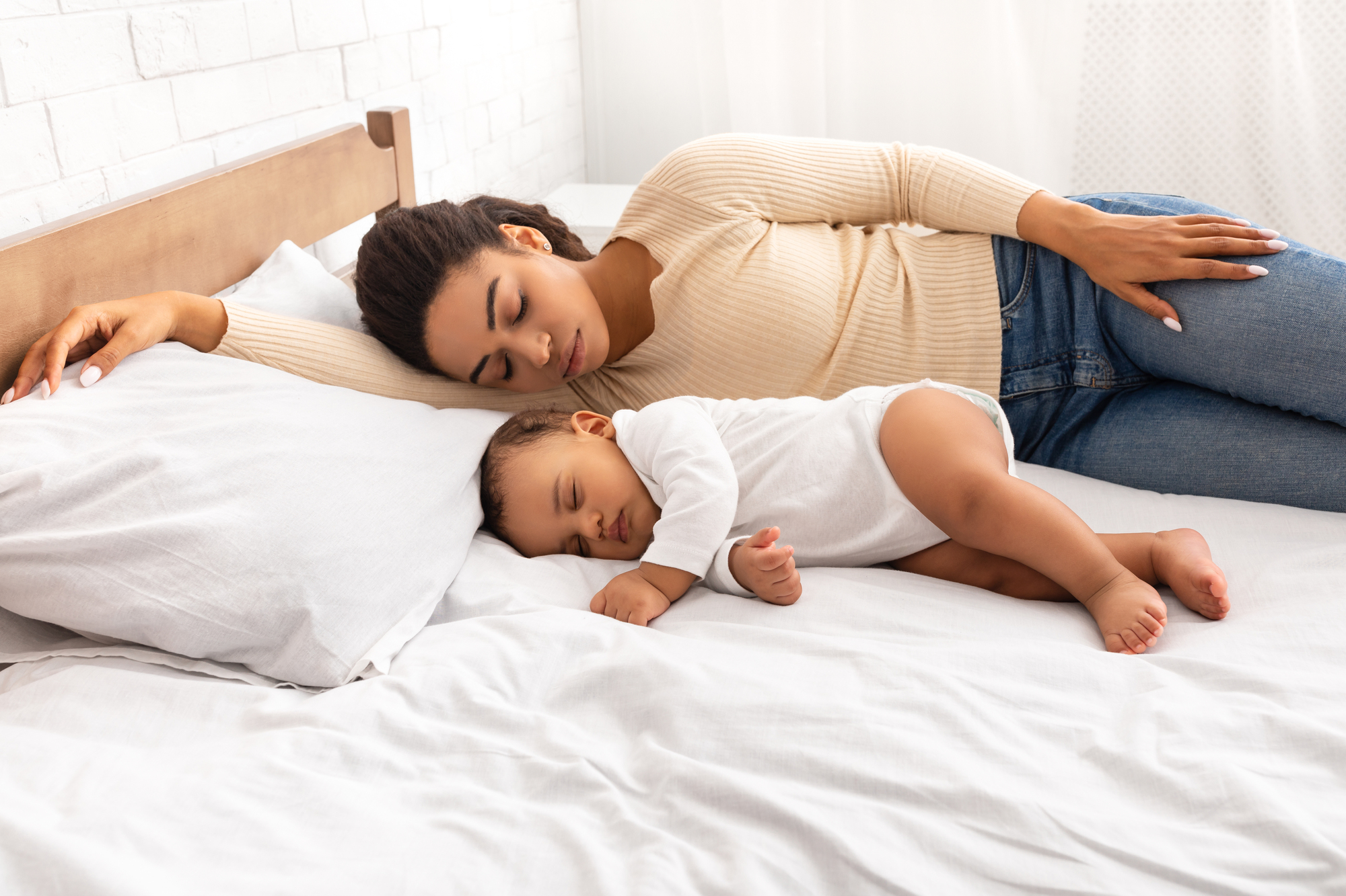 The redefined rest: how motherhood changes your relationship with sleep African mother and her baby son sleeping in bed indoor for an article about the redefined rest: how motherhood changes your relationship with sleep
