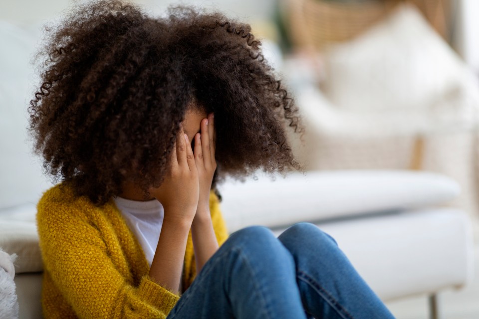 The impact of trauma on children: what parents need to know Upset preteen curly black girl sitting on floor next to couch, covering her face with palms, sad african american child crying at home, suffering from loneliness, on the impact of trauma on children.