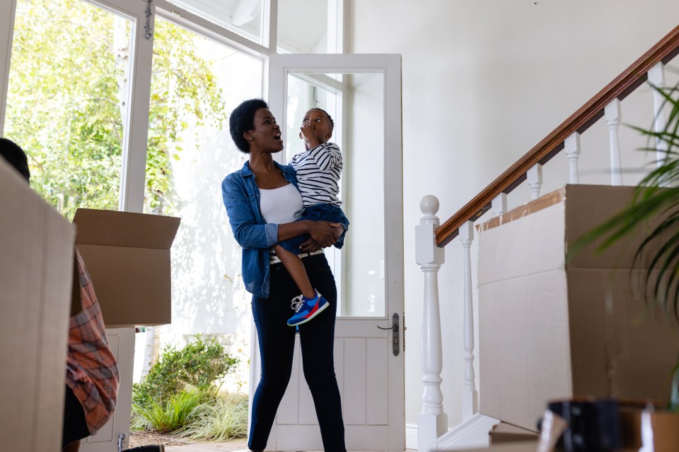 Mother holding child in new home with moving boxes — top questions to ask before hiring a moving company.