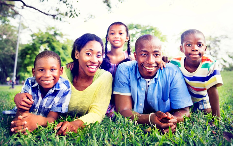 Creating a backyard oasis: how outdoor spaces boost black family wellness Creating a backyard oasis: how outdoor spaces boost black family wellness – a joyful black family with three children smiles while relaxing together on the grass in their backyard, highlighting the importance of family bonding and nature-based wellness.