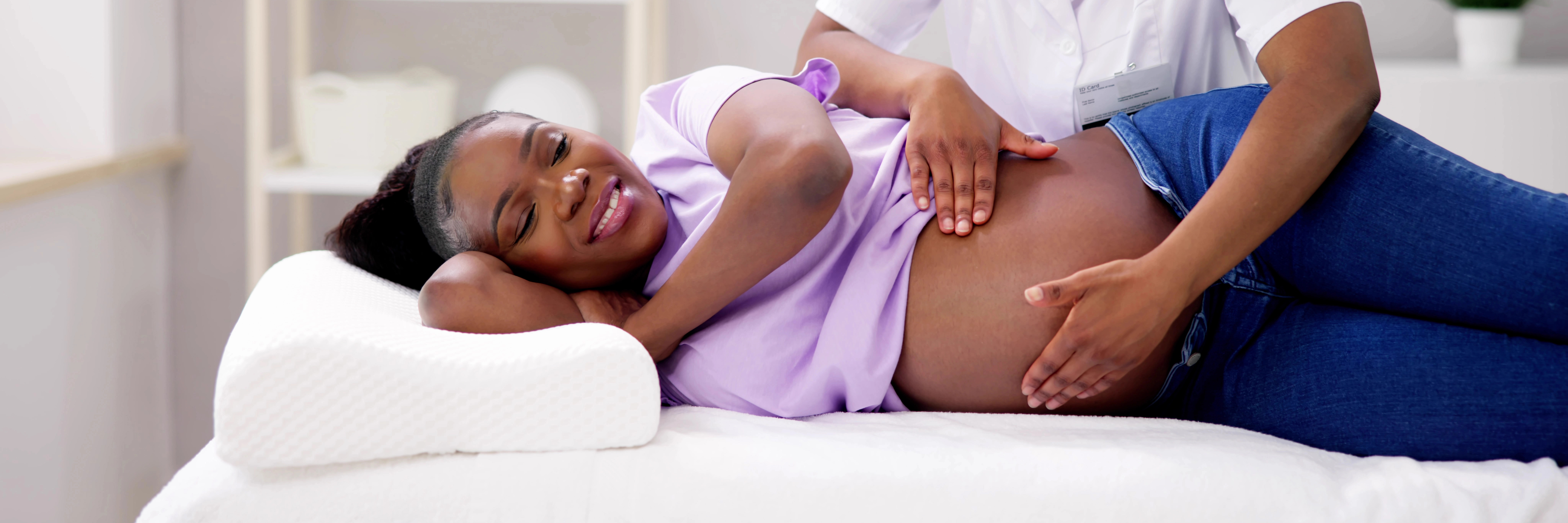 More black women are having babies over 40—here’s what that means for parenting today African american pregnant woman smiling during prenatal checkup with hands on belly, representing older motherhood and positive black maternal health for an article about more black women are having babies over 40—here’s what that means for parenting today.