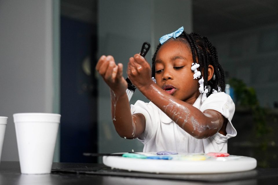 An african american girl paints her arms with paint yourself clean soaps used for bathtime.