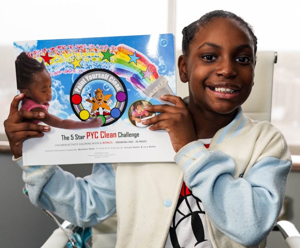 An african american girl holds up paint yourself clean paint set used for bathtime.