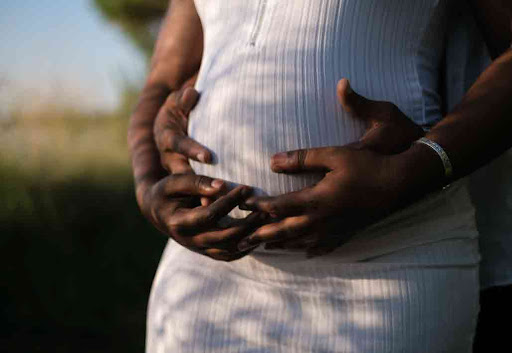 How to boost the chances of pregnancy Boost your chances of pregnancy. African american man holding wife's pregnant belly.