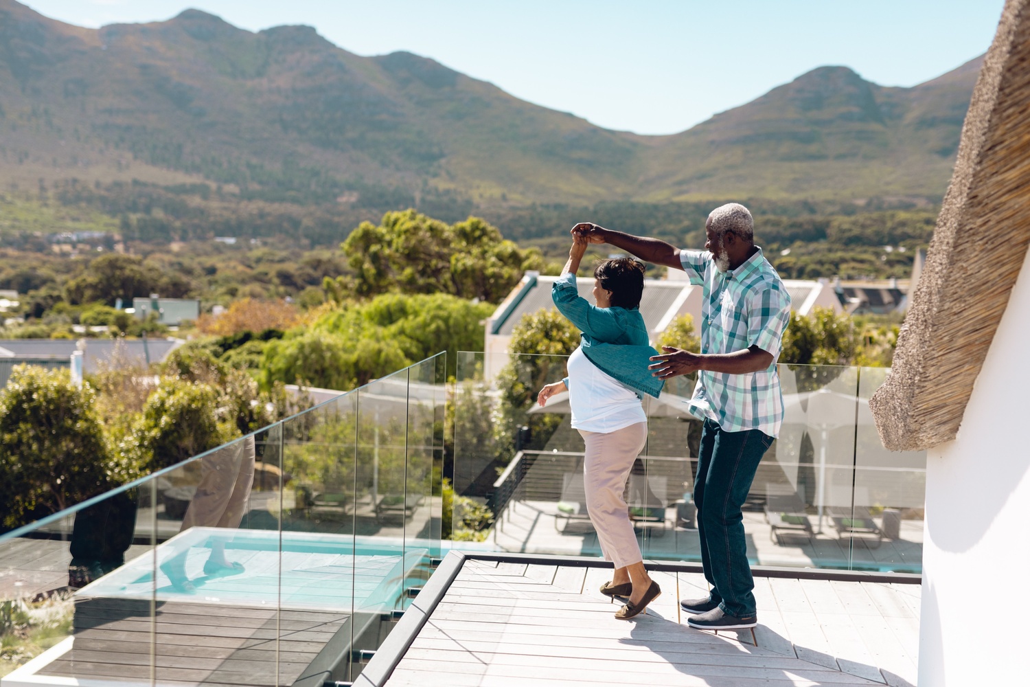 Happy grandparents enjoying time on the balcony of their family vacation home with scenic mountain views.