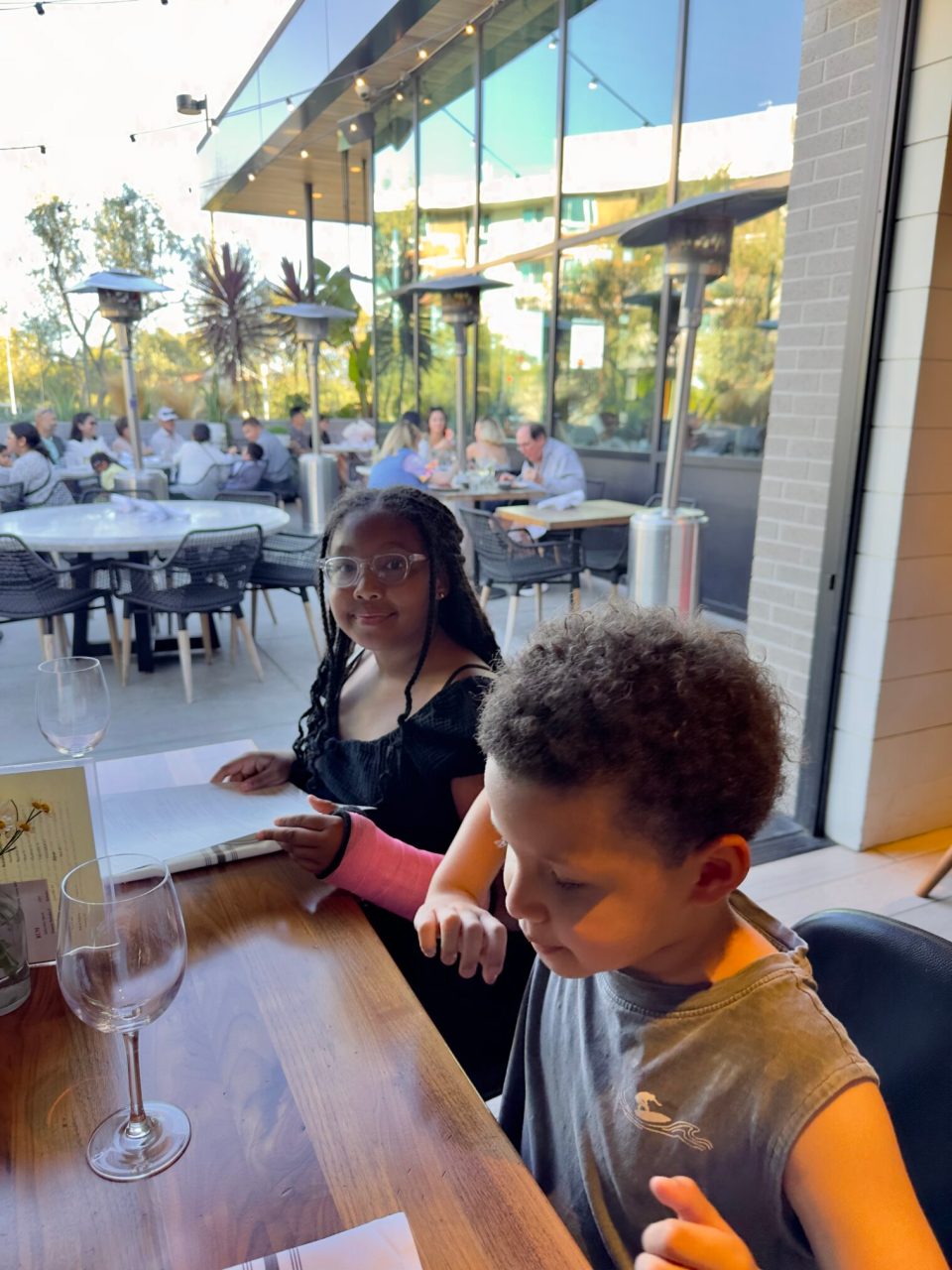 Dinner at north italia in irvine with a young black girl with braids and a pink cast on her arm and a young boy.