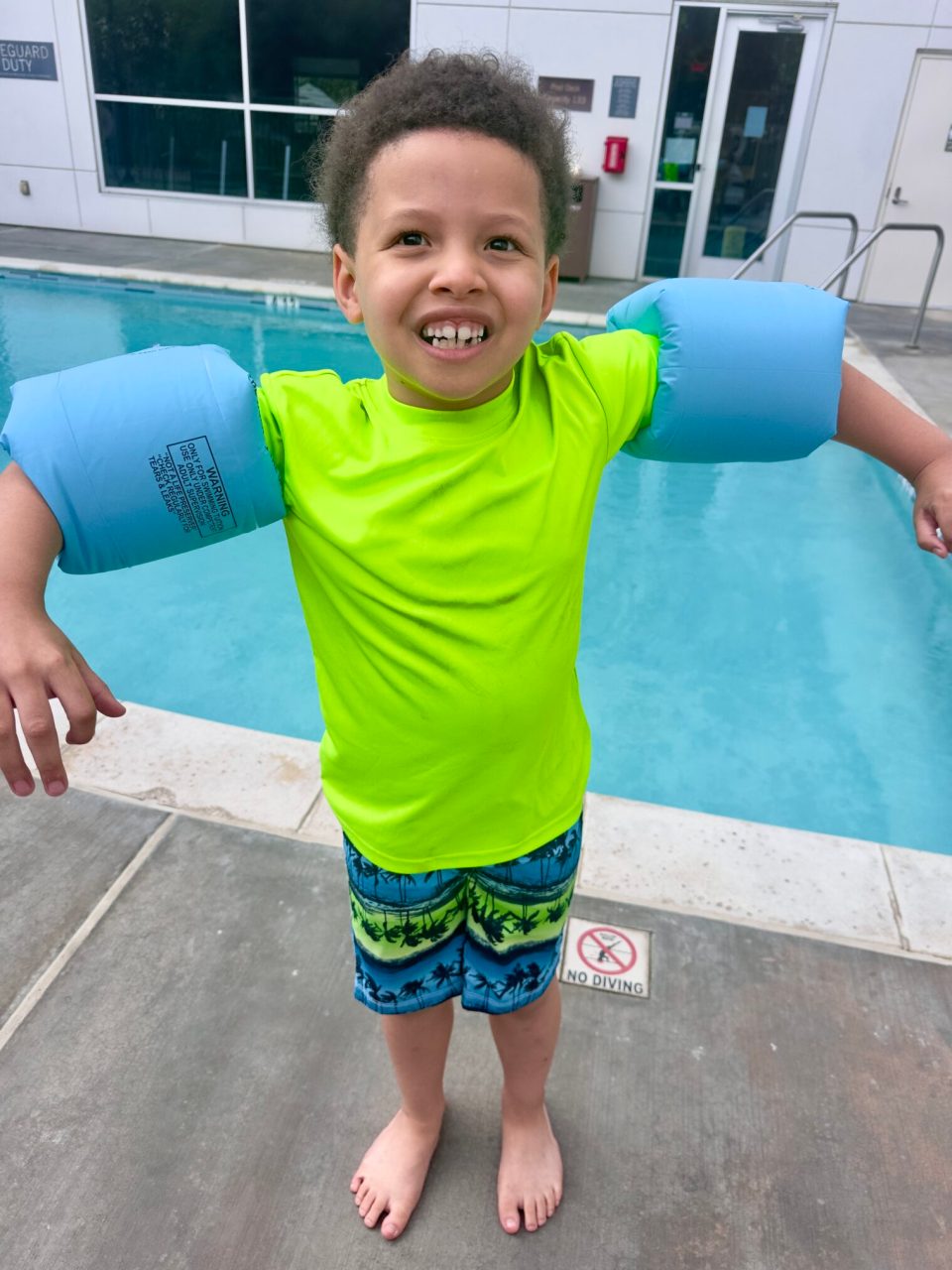 A young black boy with floaties on his arms at the swimming pool at the hyatt house in irvine, california.