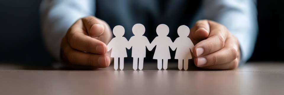 Financial planning tips for large families Hands holding a paper cutout of a family representing financial planning and unity for large families for the article, financial planning tips for large families.