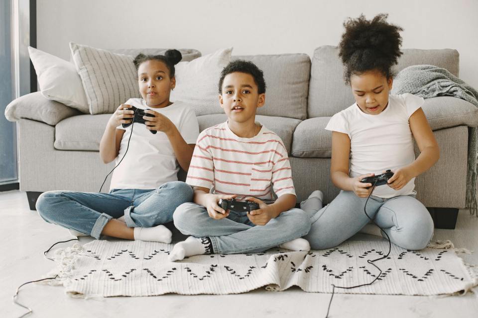 Building a gaming room to share with your kids Black kids playing video games together in a family gaming room setup designed for sharing with siblings and parents