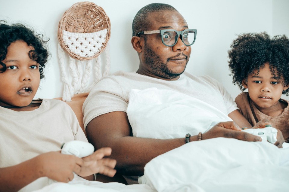 Building a gaming room to share with your kids Black father and children gaming together at home showing the joy of building a gaming room to share with your kids