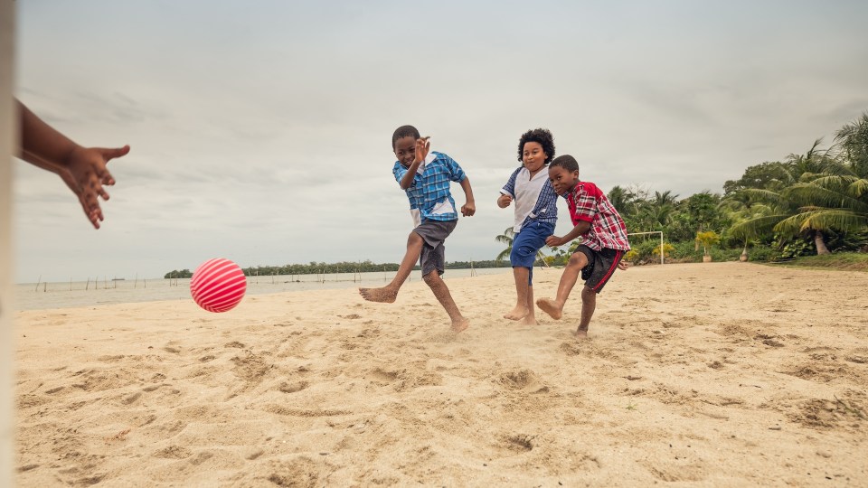Black family playing joyfully on a beach in costa rica, perfect for family-friendly travel.