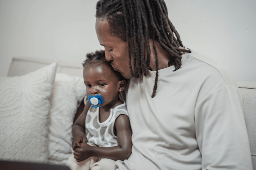 African american dad comforts his toddler who is experiencing common childhood illnesses