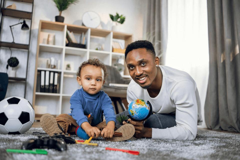 How to childproof your home: essential safety tips for new parents An african american dad is playing on the floor with his baby for an article about how to childproof your home: essential safety tips for new parents
