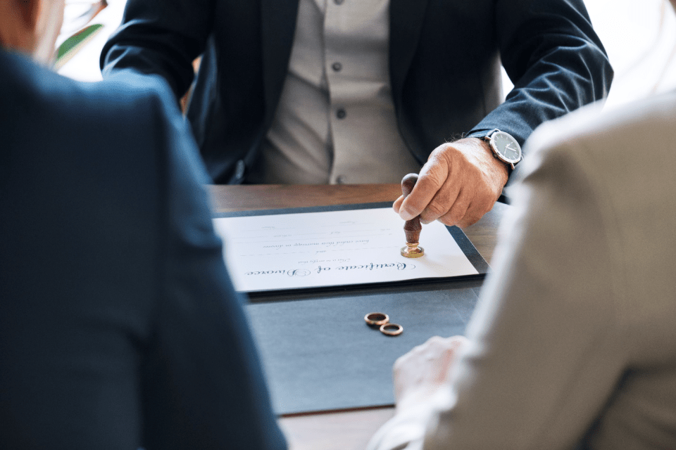 Various methods through which a marriage can be dissolved Divorce attorney in orange county stamping a certificate of divorce with wedding rings on the table between separating couple during legal proceedings to dissolve their marriage.