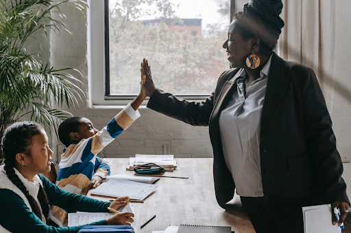 Traditional tutor giving a high-five to a student during a tutoring session, highlighting the personal connection and interactive learning experience, demonstrating the benefits of traditional tutoring compared to ai tutors vs. Traditional methods.
